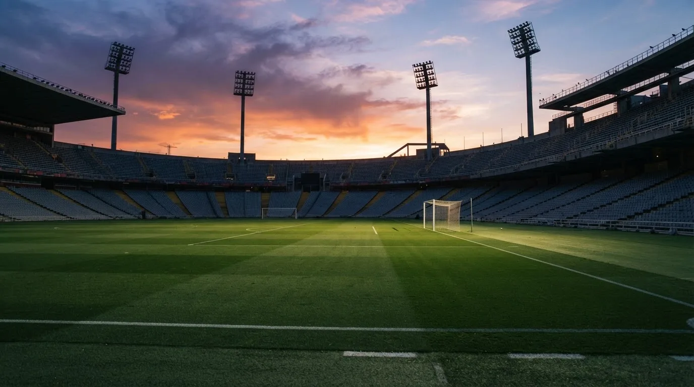 Un estadio de fútbol vacío con torres de iluminación al atardecer