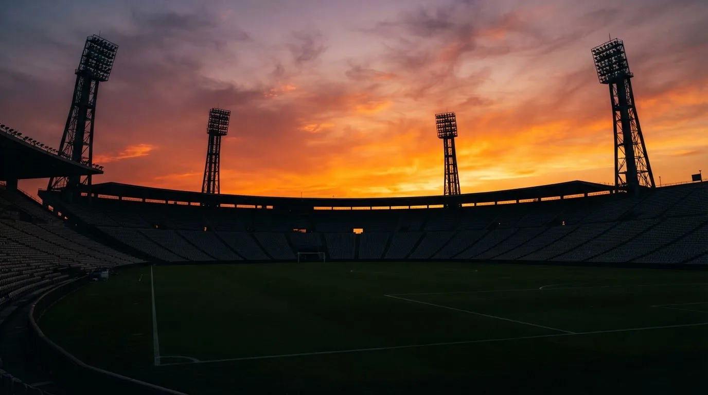 Un estadio de fútbol vacío con torres de iluminación al atardecer