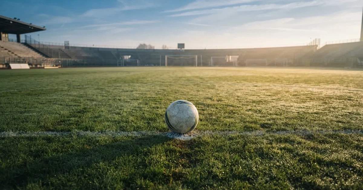 Un balón en el punto central de un campo de césped a la luz de la mañana