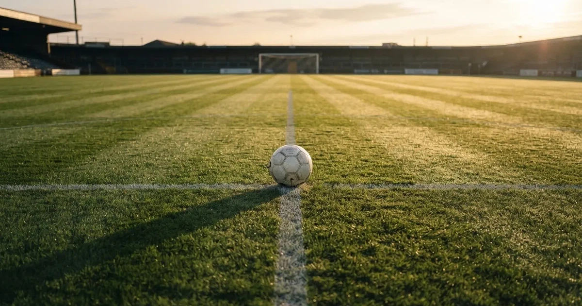 Un balón en el punto central de un campo de césped a la luz de la mañana