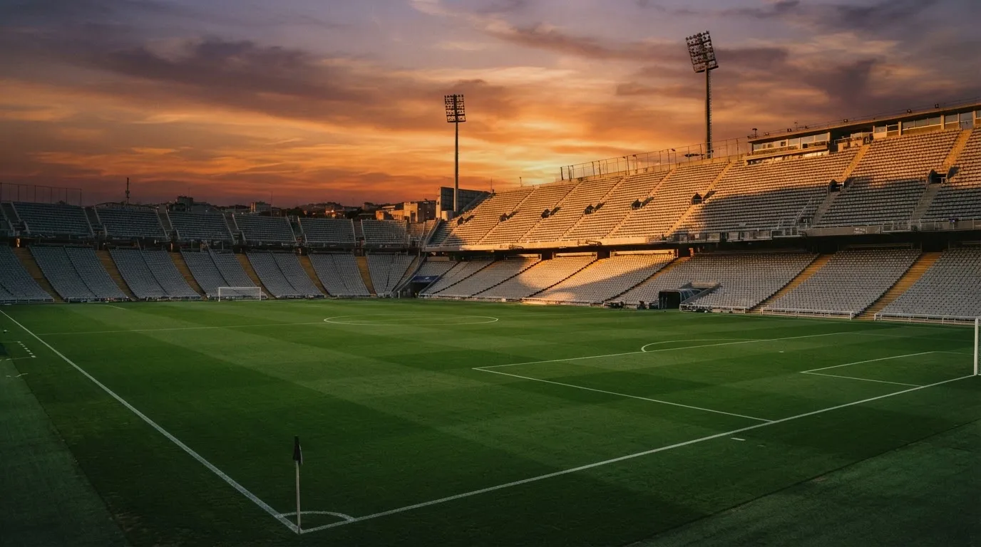 Un estadio de fútbol vacío con torres de iluminación al atardecer
