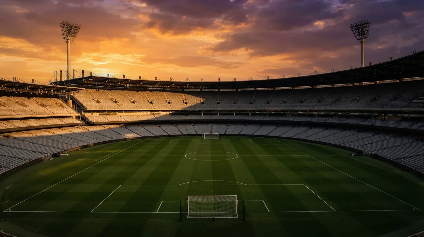 Un estadio de fútbol vacío con torres de iluminación al atardecer