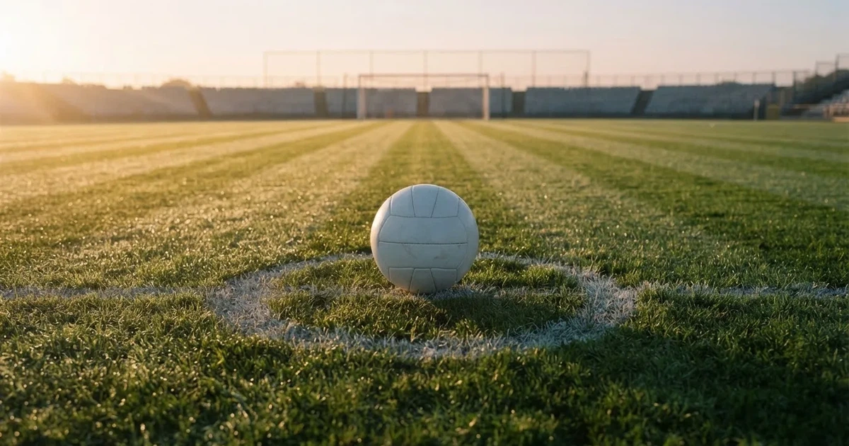 Un balón en el punto central de un campo de césped a la luz de la mañana