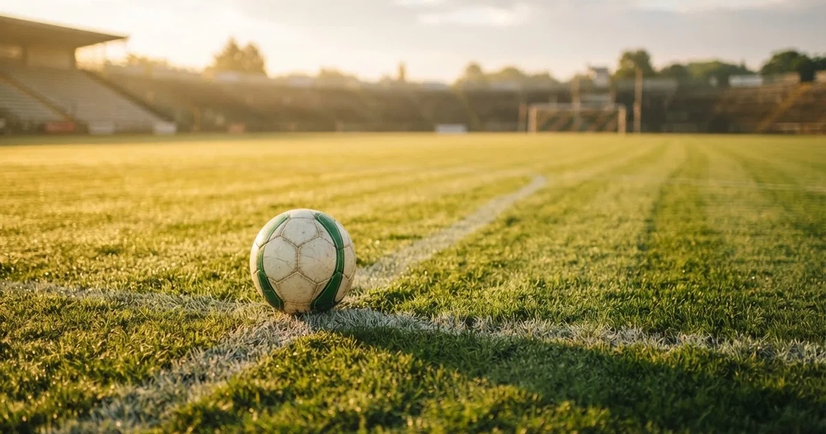 Un balón en el punto central de un campo de césped a la luz de la mañana