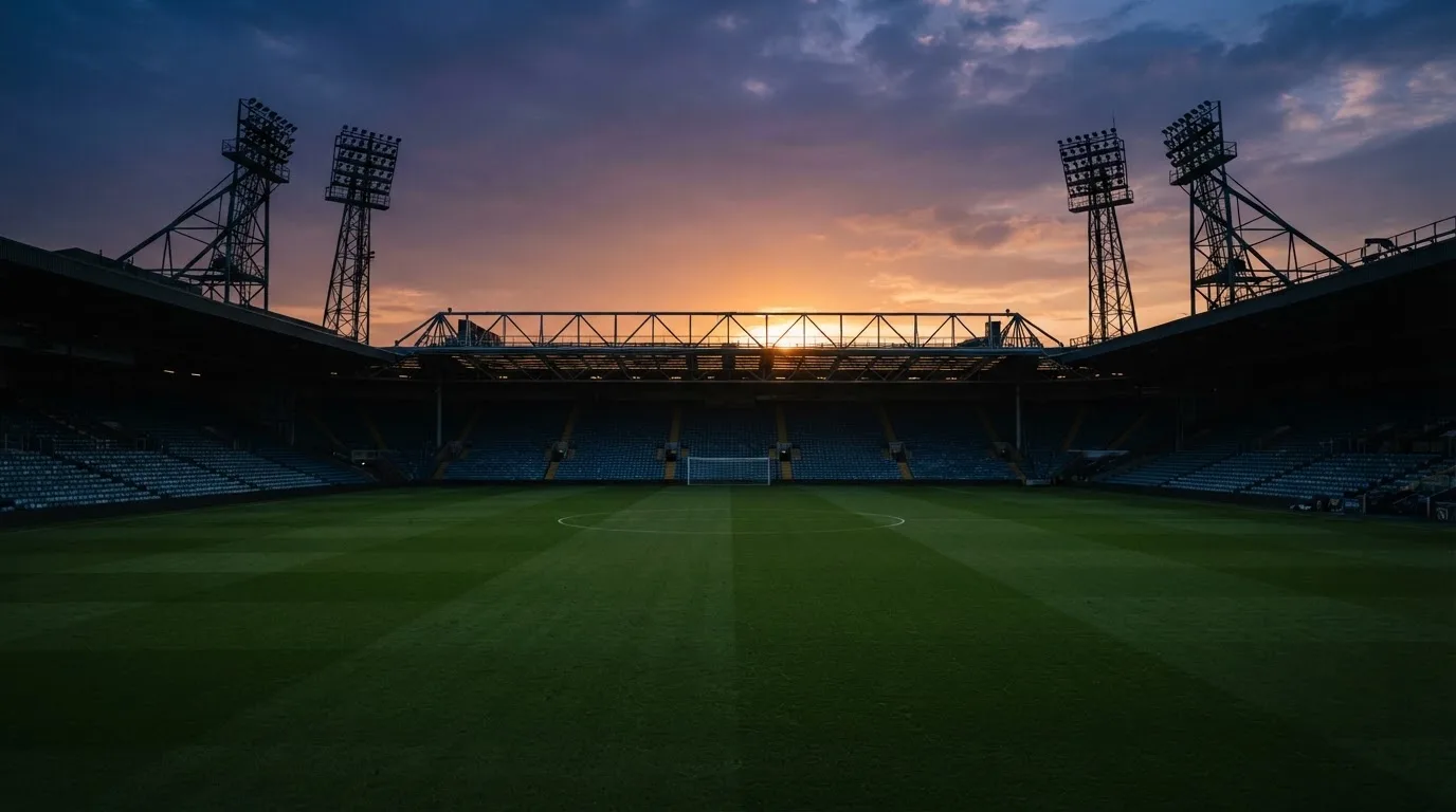 Un estadio de fútbol vacío con torres de iluminación al atardecer