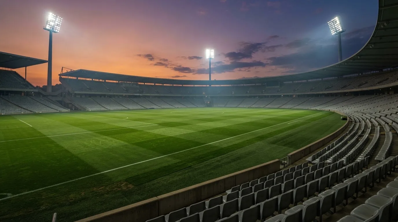 Un estadio de fútbol vacío con torres de iluminación al atardecer
