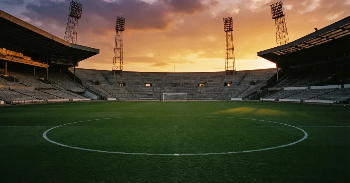 Un estadio de fútbol vacío con torres de iluminación al atardecer