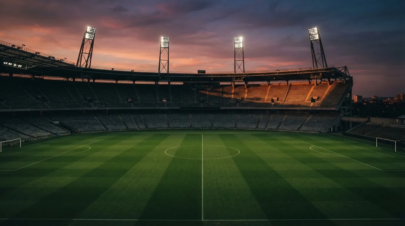 Un estadio de fútbol vacío con torres de iluminación al atardecer