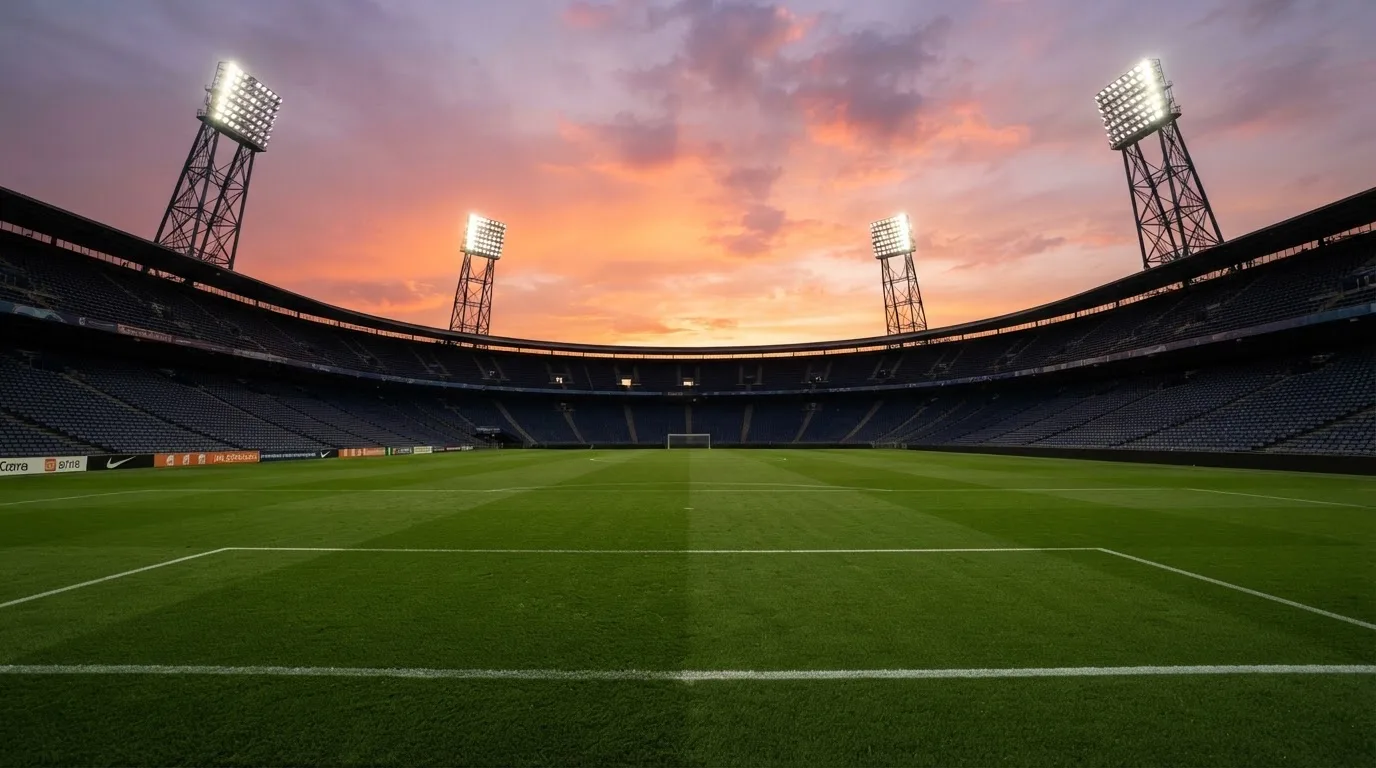 Un estadio de fútbol vacío con torres de iluminación al atardecer