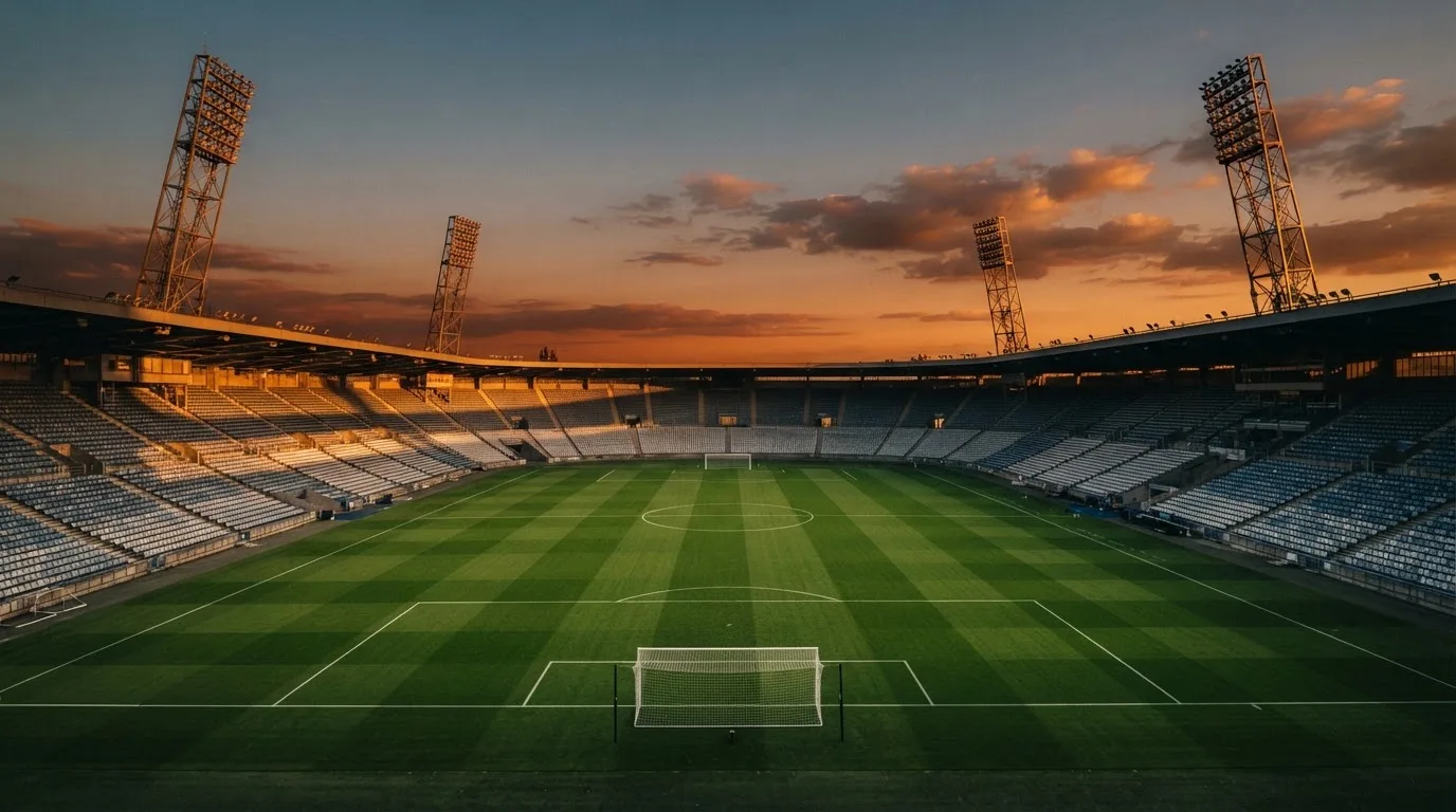 Un estadio de fútbol vacío con torres de iluminación al atardecer