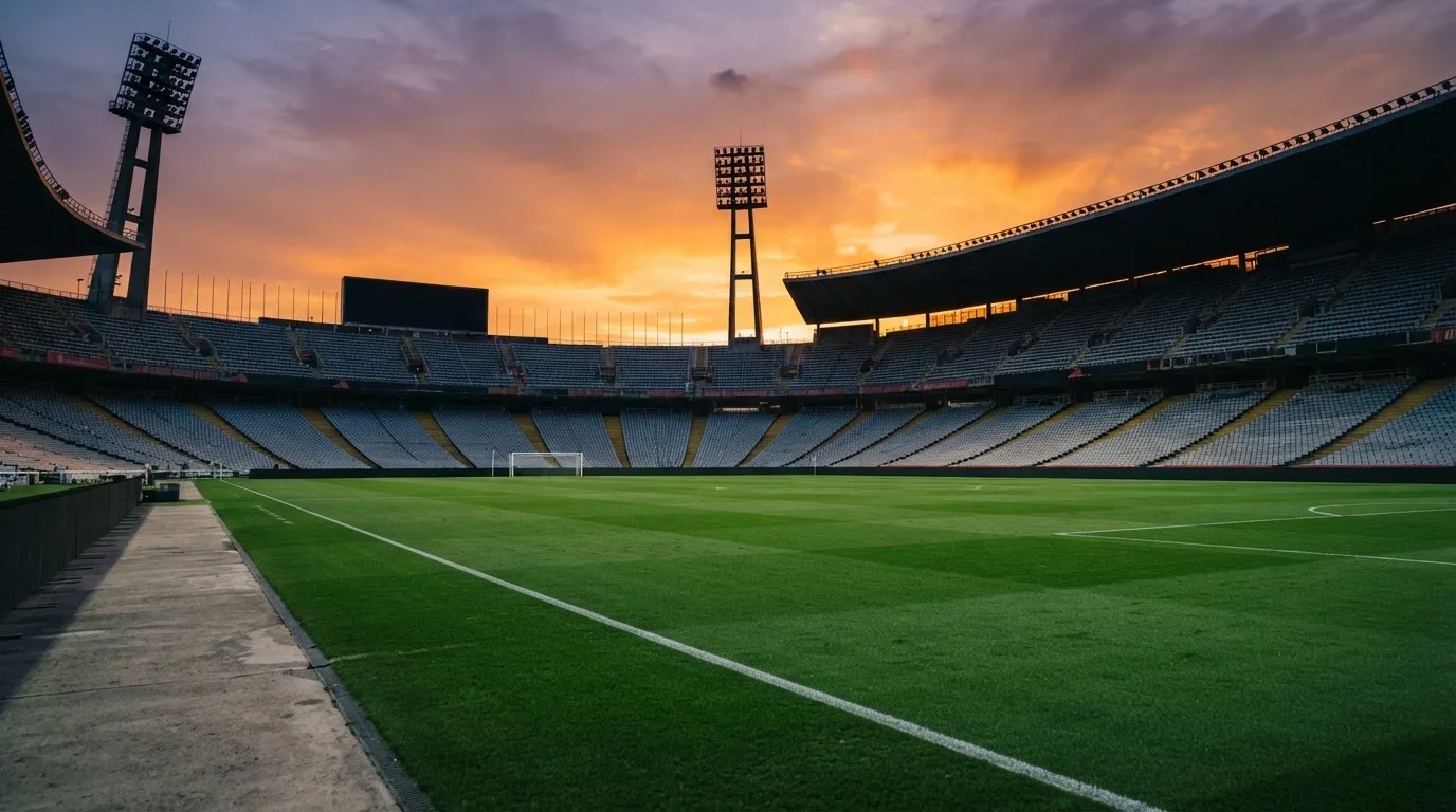 Un estadio de fútbol vacío con torres de iluminación al atardecer