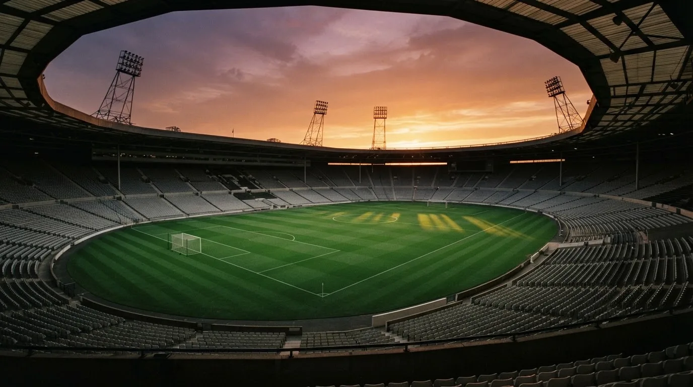 Un estadio de fútbol vacío con torres de iluminación al atardecer