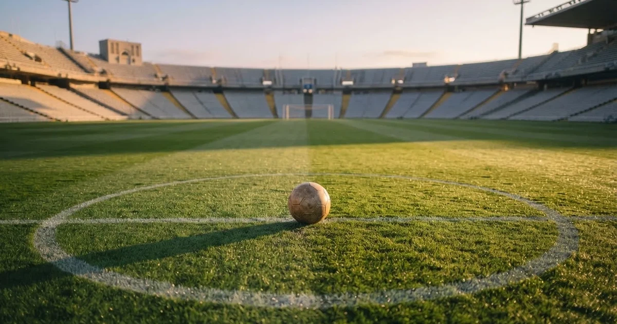 Un balón en el punto central de un campo de césped a la luz de la mañana