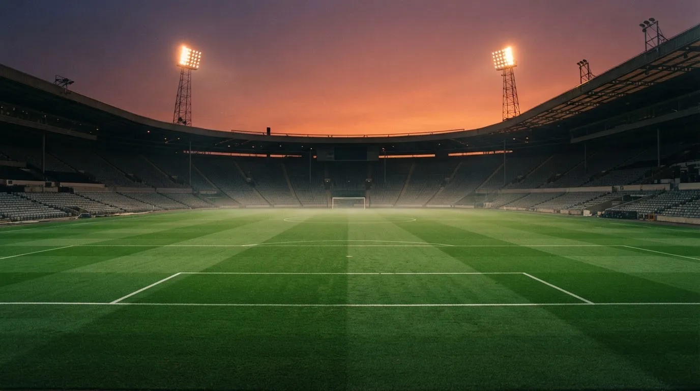 Un estadio de fútbol vacío con torres de iluminación al atardecer