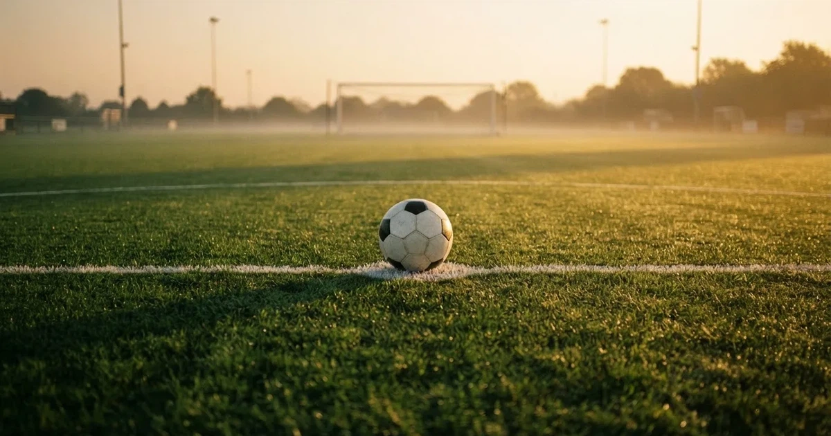 Un balón en el punto central de un campo de césped a la luz de la mañana