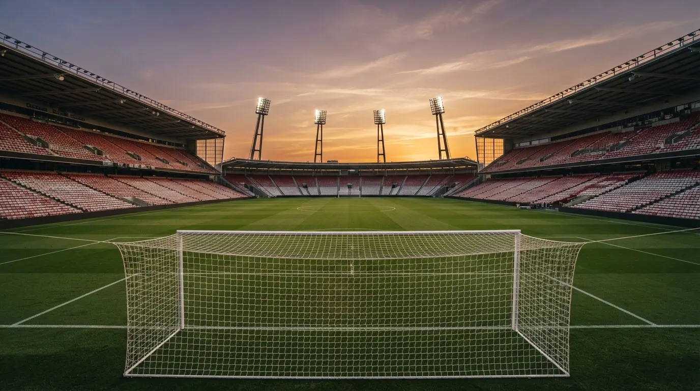 Un estadio de fútbol vacío con torres de iluminación al atardecer