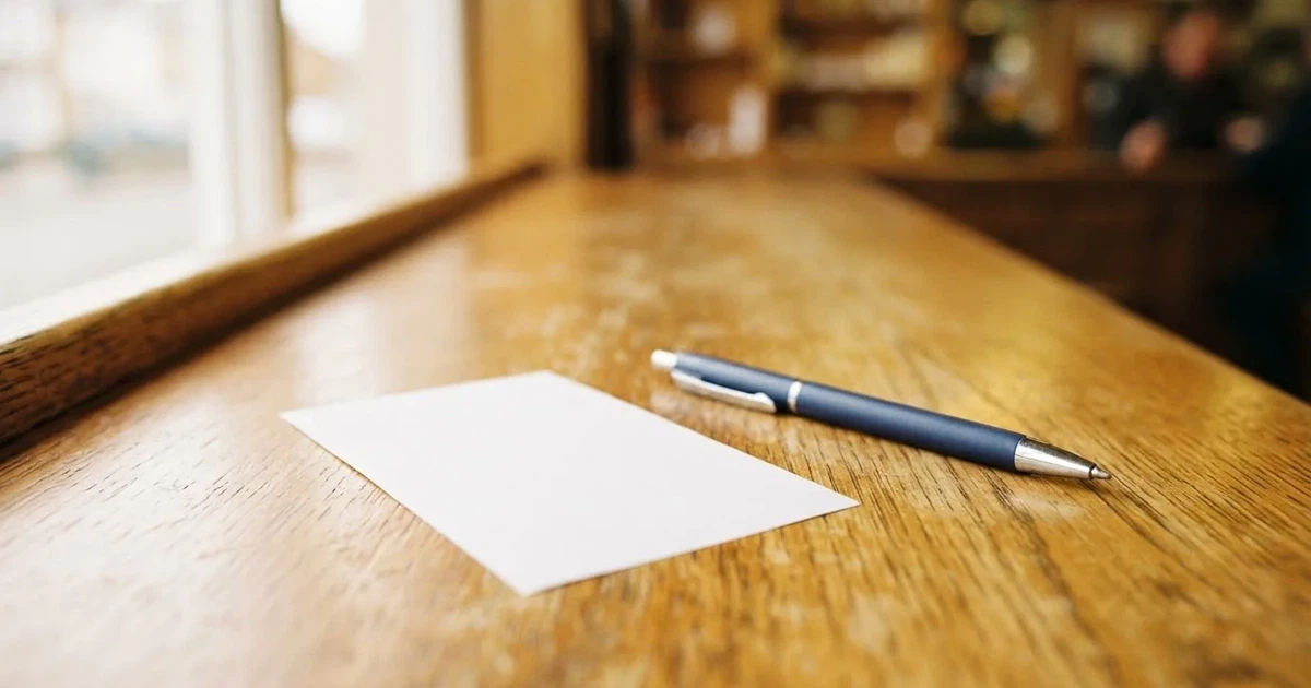 Un boleto de papel en blanco junto a un bolígrafo sobre un mostrador de madera