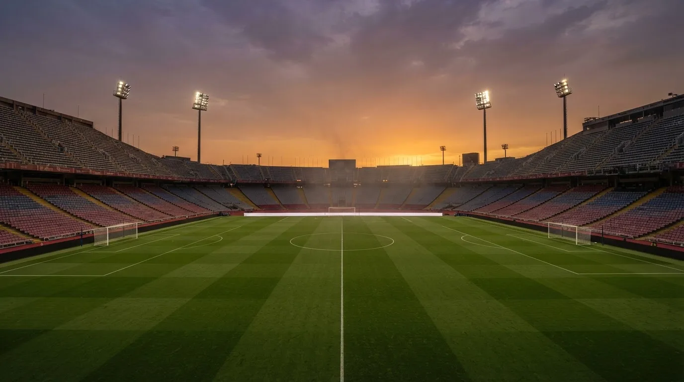 Un estadio de fútbol vacío con torres de iluminación al atardecer